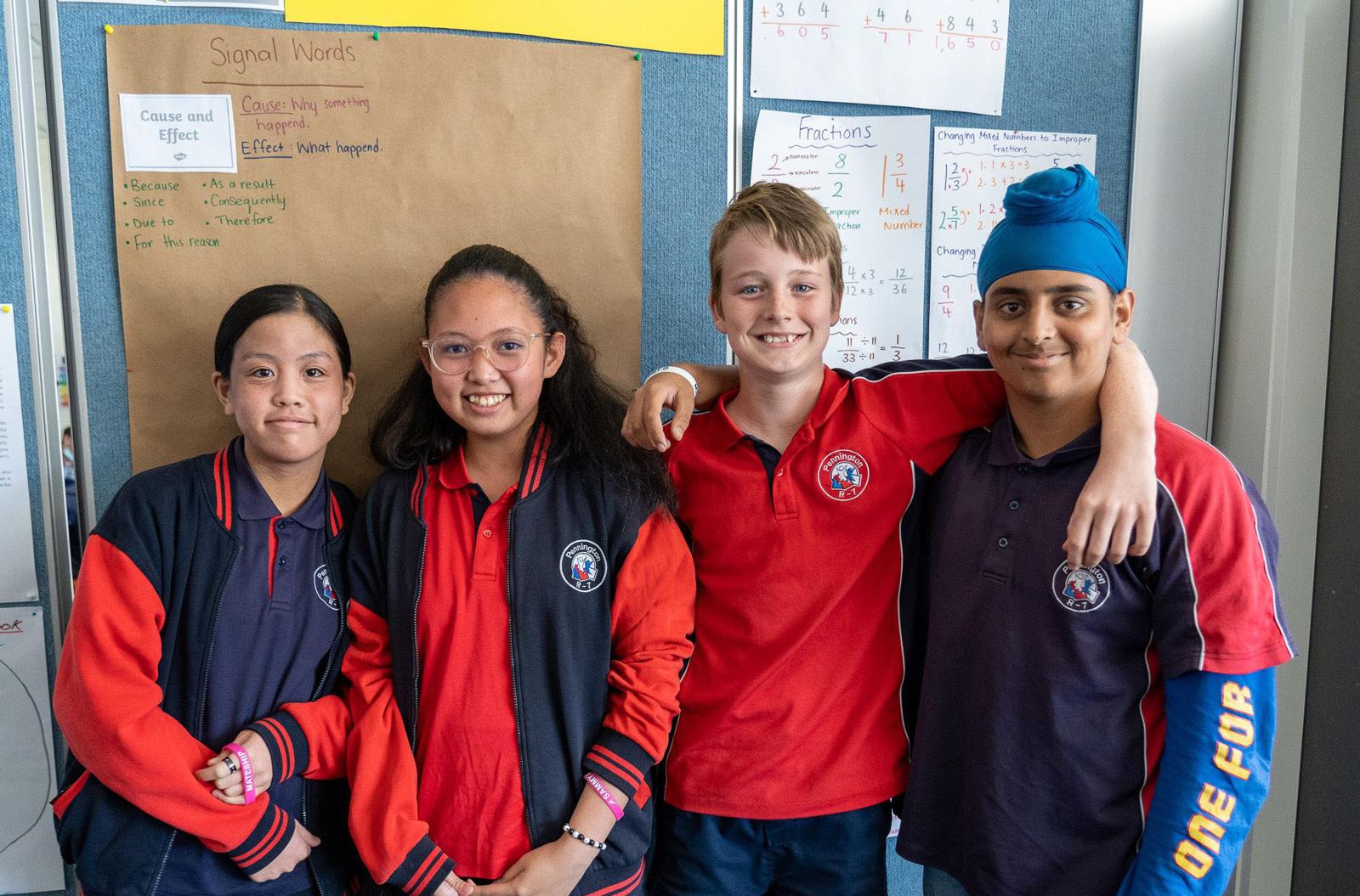 Four smiling primary school students in uniform standing together